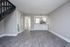 Modern apartment interior showcasing a bright open-plan kitchen and living area with sleek flooring and elegant staircase.