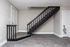 Charming apartment interior featuring a sleek black staircase and elegant gray flooring, perfect for modern living.