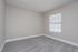 Bright and airy bedroom with plush carpeting and large window, perfect for relaxation and comfort.