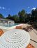 Inviting outdoor pool area with stylish lounge chairs and a decorative round table against a clear blue sky, perfect for relaxation and sunbathing.