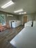 Bright and modern laundry room featuring multiple washing machines, cozy seating, and large windows for natural light.