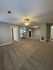 Spacious apartment interior featuring plush carpeted living area with ceiling fan, open access to a modern kitchen.