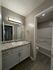 Contemporary bathroom with granite countertop, modern lighting, and elegant wood flooring.