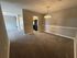 Inviting apartment interior with plush carpeting, elegant chandelier lighting, and sleek kitchen appliances.