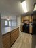 Inviting kitchen with modern black appliances, spacious wooden cabinetry, and open layout leading to a bright living area.