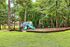 Charming outdoor playground surrounded by lush trees, featuring vibrant slides and swings, perfect for family fun in a serene setting.