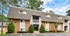 Charming brick apartment building with shingled upper facade, surrounded by lush greenery, offering serene and inviting living spaces.