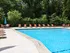 Inviting outdoor pool area with vibrant orange loungers and lush green surroundings, perfect for relaxation.