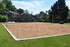 Inviting sand volleyball court nestled in a lush green backyard, perfect for outdoor fun and relaxation.