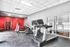 Modern fitness center featuring state-of-the-art machines, vibrant red accent wall, and bright lighting for an energetic workout atmosphere.