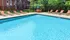 Inviting outdoor pool area with sparkling blue water, surrounded by comfortable lounge chairs and lush greenery, perfect for relaxation and enjoyment.