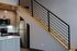 Contemporary kitchen with stainless steel appliances and sleek wooden cabinetry, complemented by a stylish staircase with modern railing.
