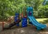 Inviting outdoor playground with vibrant blue slides, climbing features, and surrounded by lush greenery, perfect for family fun.