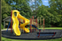 Vibrant playground with a twisting yellow slide and multi-level climbing structures surrounded by lush greenery, offering a perfect place for outdoor fun and adventure.