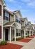 Charming townhouse row with inviting porches, manicured landscaping, and serene community setting under a bright blue sky.