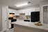 Modern kitchen with sleek granite countertops, white cabinetry, and black appliances, offering stylish functionality and ample storage space.