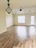 Bright, airy living room with elegant light fixtures, ceiling fan, and sleek wood flooring, leading to a sunlit window and a glass door.