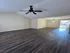 Spacious living room with elegant dark wood flooring, ceiling fan, and abundant natural light near the inviting entrance.