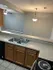 Bright kitchen with open layout featuring a double sink, granite countertops, and view into a spacious living room with elegant lighting.