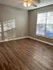Bright, sunlit room with elegant wood flooring and modern ceiling fan, perfect for a cozy living space.