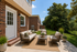 Charming outdoor patio with elegant wicker furniture, lush greenery, and inviting space for relaxation.