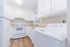 Inviting kitchen with modern white cabinets, sleek appliances, and stylish wood flooring, perfect for culinary adventures.