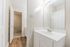 Bright and inviting bathroom with a modern white vanity, large mirror, and elegant wood flooring.