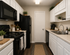Chic, modern kitchen with sleek counters, black appliances, and elegant white cabinetry, accented by greenery for a fresh look.