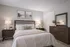 Cozy bedroom featuring elegant wood furniture, soft lighting, and tasteful wall art, creating a welcoming and serene atmosphere.
