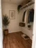 Chic walk-in closet with stylish wooden flooring, a framed botanical print, and ample organized storage featuring hanging clothes and woven baskets.