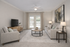 Elegant living room with plush gray seating, artistic decor, and abundant natural light through large windows, creating a cozy and inviting atmosphere.