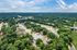 Breathtaking aerial view of a lush green suburban neighborhood with multiple apartment buildings, nestled amid trees, offering easy access to major roadways.