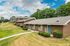 Charming brick apartment complex with well-manicured lawns and lush greenery, featuring a tranquil neighborhood setting under a bright blue sky.