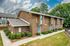 Charming brick apartment complex with modern blue doors, surrounded by lush greenery and nestled in a tranquil neighborhood.