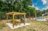 Inviting outdoor area featuring a wooden pergola with picnic tables and a barbecue, adjacent to a refreshing pool with vibrant lounge chairs.