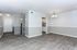 Bright and airy living space with elegant wood flooring, modern lighting, and a view into a sleek kitchen area.