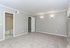 Spacious bedroom with soft carpet, elegant wall sconces, and adjoining private bathroom in a modern apartment.