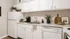 Charming kitchen with modern white cabinetry, sleek appliances, and stylish decor accents offering a welcoming and functional space.