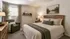 Cozy bedroom featuring a plush bed with earthy tones, soft lighting, and elegant decor creating a serene retreat.
