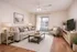 Inviting living room with elegant decor, featuring a comfortable beige sofa, cozy armchair, and stylish wooden coffee table. Natural light floods through large glass doors, highlighting the serene and modern ambiance.