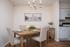 Charming dining area with elegant chandelier, cozy table setting for six, and inviting natural decor, adjacent to a modern kitchen.