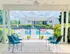 Inviting outdoor seating area overlooking a serene swimming pool, framed by lush greenery and a charming residential view.