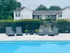 Inviting apartment complex featuring a crystal-clear swimming pool with modern lounge chairs and lush greenery, perfect for relaxation and leisure.