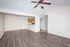 Spacious open-plan living area with elegant wooden flooring and a modern ceiling fan, leading to a cozy kitchen with wooden cabinets.