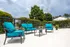 Chic outdoor patio area with vibrant teal seating, lush greenery, and a stylish umbrella, ideal for relaxation and social gatherings.