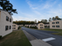 Charming residential neighborhood with well-maintained multi-unit brick apartments and lush green lawns under a bright blue sky.