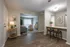 Apartment dining area with breakfast bar, wood-style flooring, and adjoining living room at The Lodge Apartments in Columbus, GA. Inviting living space featuring stylish hardwood floors, a cozy seating area with teal and pink accents, and a breakfast bar with elegant dining chairs.