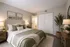 Inviting bedroom with a serene palette, featuring a plush bed with green accents, chic wooden furniture, and soft lighting for a cozy retreat. Virtually staged apartment bedroom with neutral furnishings, carpet flooring, large double-door closet, and natural light at The Lodge Apartments in Columbus, GA.