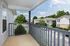 Charming balcony with a view of a serene residential neighborhood, showcasing lush greenery and well-maintained buildings under a bright blue sky.