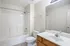 Bright and modern bathroom featuring a full bathtub, spacious vanity, and sleek tile flooring.